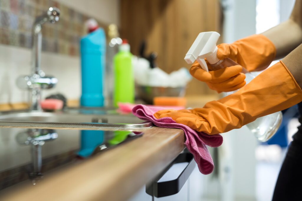woman-while-cleaning-surface-kitchen-desk-with-sponge-her-rubber-gloves-housework-min